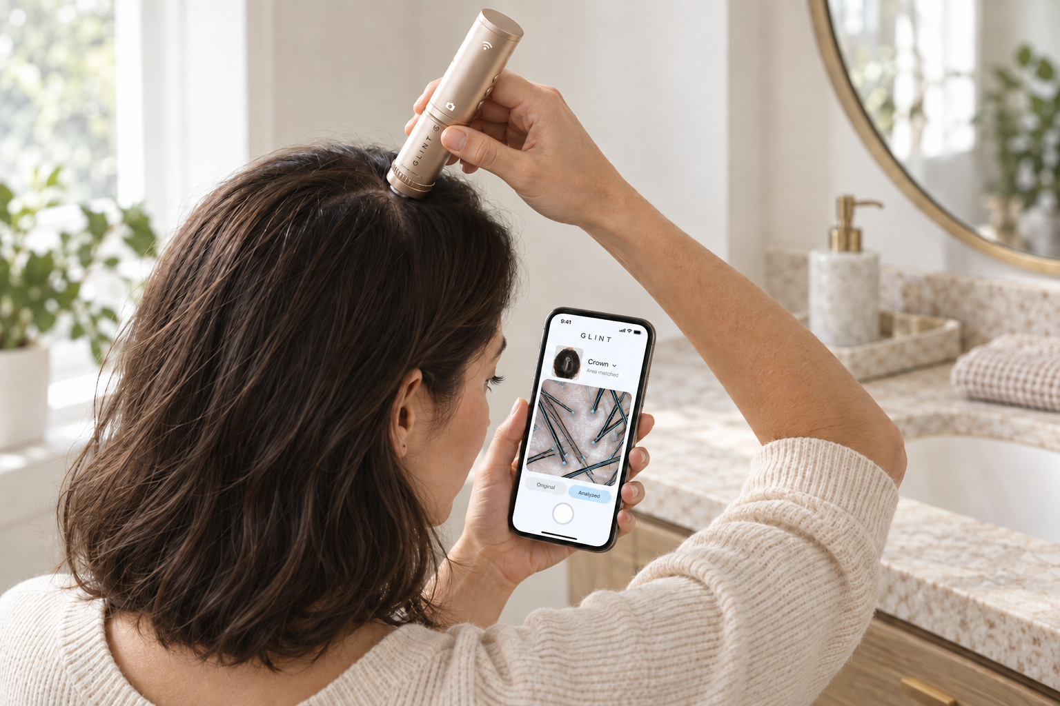 A woman scans her crown with GLINT while viewing her scalp on her phone